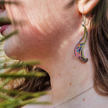 Load image into Gallery viewer, Always Leaf a Little Room for Whimsy earrings, swirly leaf-shaped earrings with little cutouts hand-painted titanium in yellow, pink, and blue modeled on woman's ear