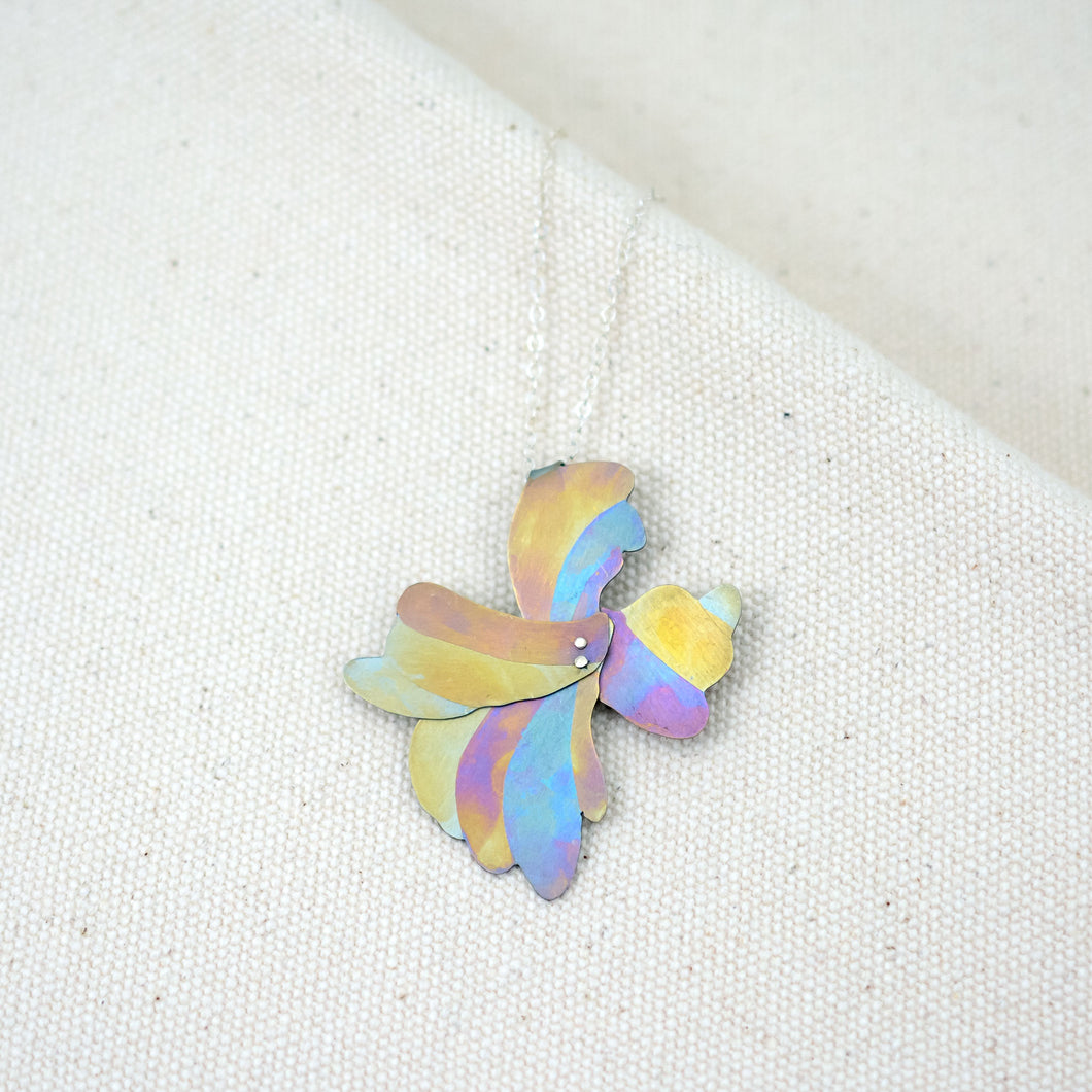 Her Glow at Golden Hour necklace, organic floral shaped pendant hand-painted titanium with yellow, blue, and pink stripes 