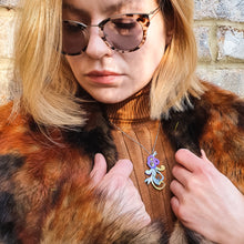 Load image into Gallery viewer, woman modeling She Will Bloom in a Dark Room necklace, a hand-painted titanium purple flower pendant with curly vines and leaves