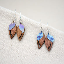 Load image into Gallery viewer, the two colorful hand painted patterns of The Dew at Dawn earrings, upside-down teardrop-shaped wooden earrings with a slit down the side and a blue teardrop-shaped piece of titanium riveted on top
