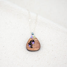 Load image into Gallery viewer, hand crafted The Root of Things necklace, a rounded triangular wooden and titanium necklace with a flower carved out of the wood to see the purple hand painted titanium underneath
