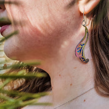 Load image into Gallery viewer, Always Leaf a Little Room for Whimsy earrings, swirly leaf-shaped earrings with little cutouts hand-painted titanium in yellow, pink, and blue modeled on woman&#39;s ear
