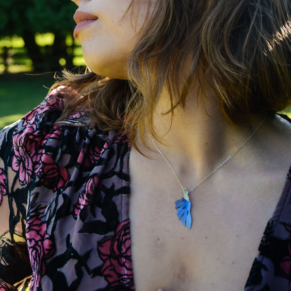woman modeling Her Radiance Renewed necklace, a blue bird pendant hand-painted titanium