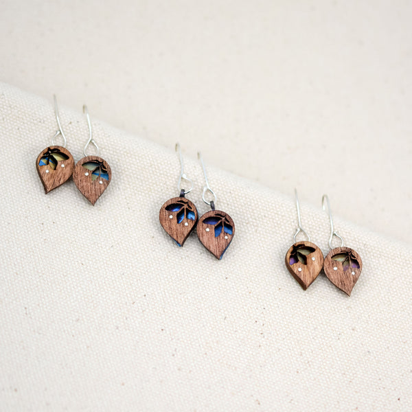 the three different hand painted patterns of The Freedom to Flourish flower earrings, upside down teardrop shaped wooden and titanium earrings with a small flower cutout