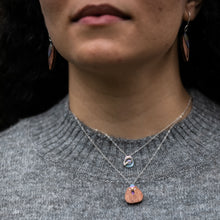 Load image into Gallery viewer, close-up of woman&#39;s neckline wearing The Rhythm of Rain necklace, a small teardrop pendant, in blue layered with The Root of Things necklace
