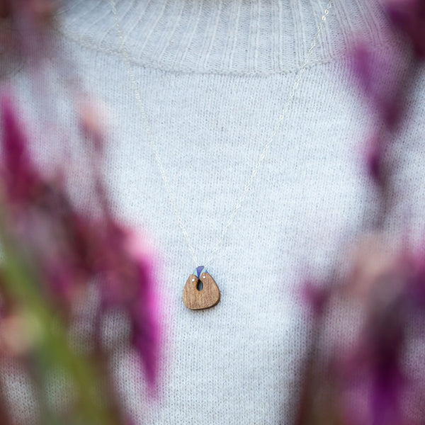 woman's neckline wearing The Root of Things necklace over a light grey sweater